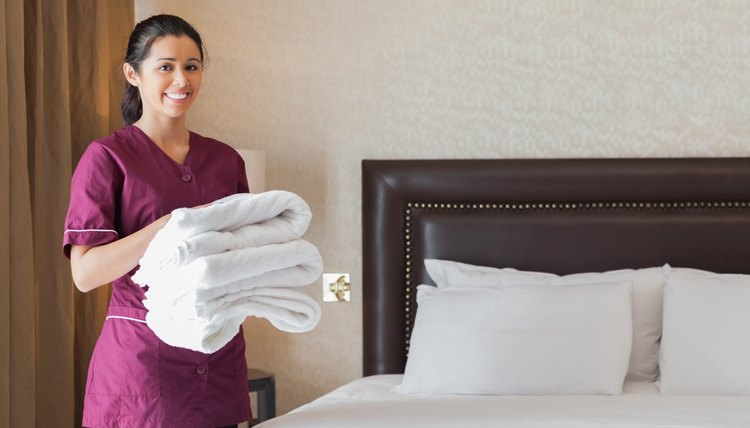 Hotel maid holding pile of fresh towels