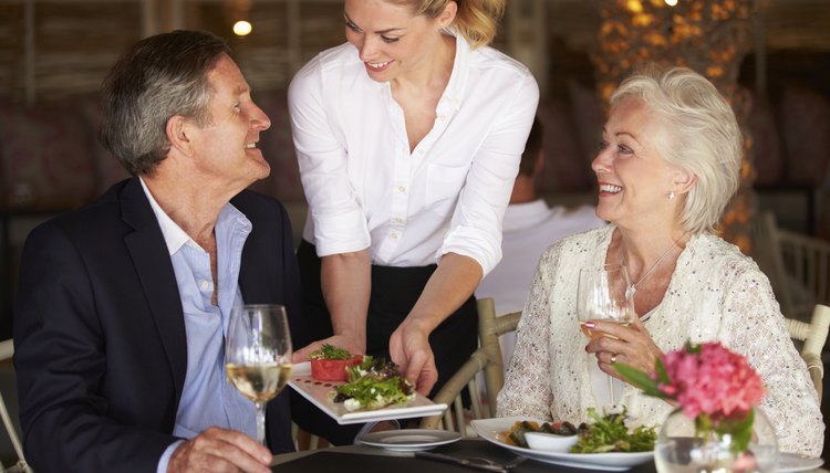 Waitress Serving Food To Senior Couple In Restaurant