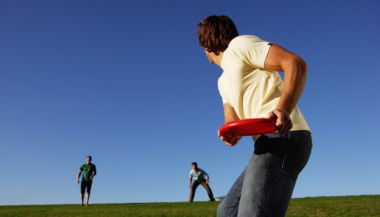 Three men playing with flying disc in park