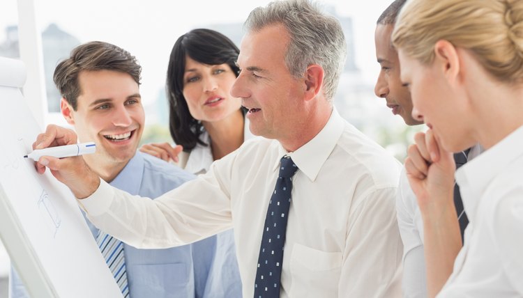 Smiling colleagues watching businessman writing on whiteboard
