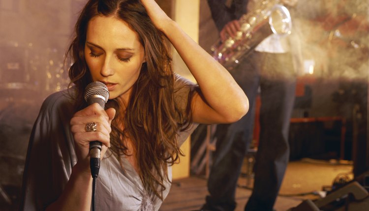 Female Singer Performing on Stage With a Man in the Background Playing a Saxophone