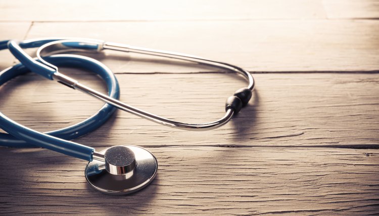 Medical stethoscope dramatically lit on a wooden table