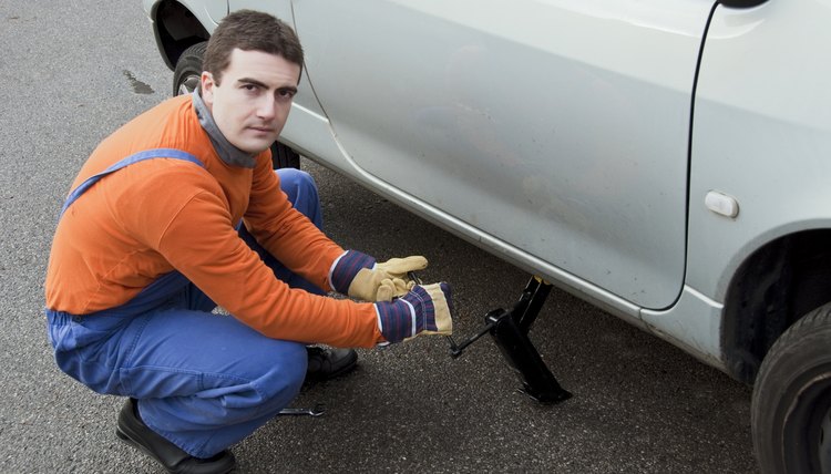 Mechanic lifts car with the jack changing a wheel