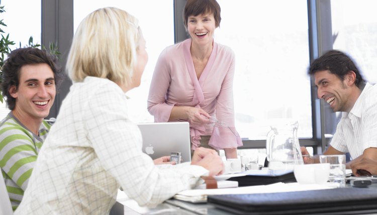 Businesswomen and men laughing sitting at conference table