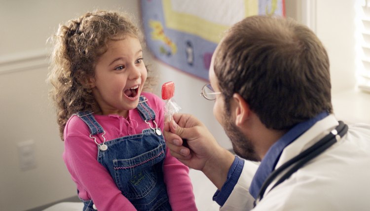 a little brunette caucasian girl recieves a lollipop as a special treat from her doctor