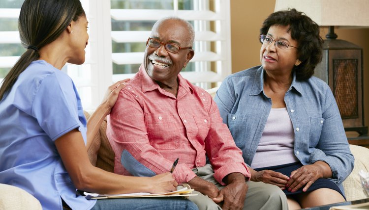 Nurse Making Notes During Home Visit With Senior Couple