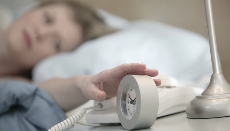 Woman reaching for alarm clock