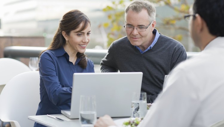 Man and woman look at a computer in cafe.