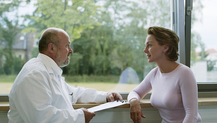 Male doctor sitting with female patient by window, side view