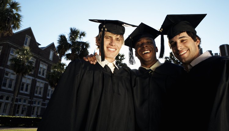 Young men in graduation cap and gowns smiling, portrait, close-up