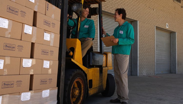 Two men working, one driving forklift, one holding clipboard