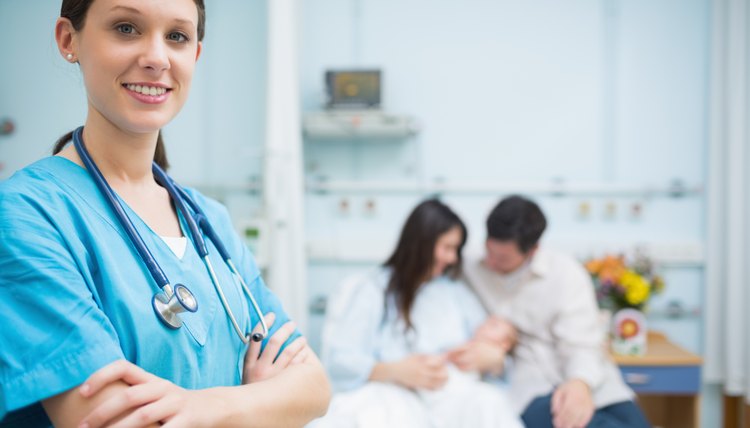 Doctor crossing her arms in the foreground of a room with a family with a new born baby