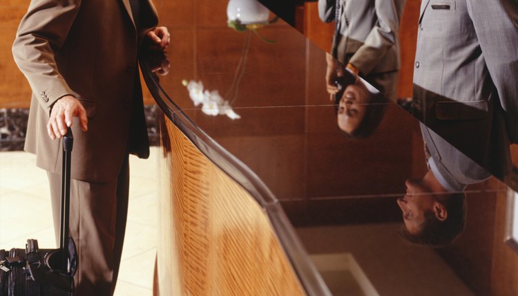 Man checking in at hotel reception desk, side view