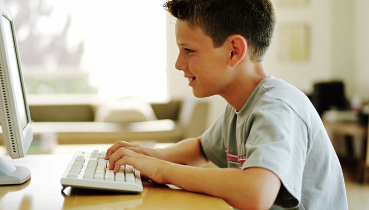 Boy (9-11) at table using computer, profile