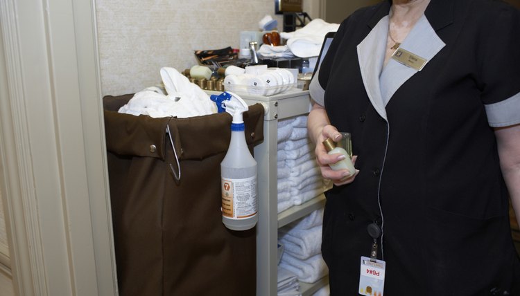 Hotel maid at housekeeping cart in hallway, mid section
