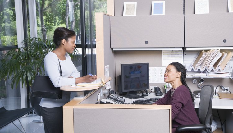 Woman talking with secretary in office, side view