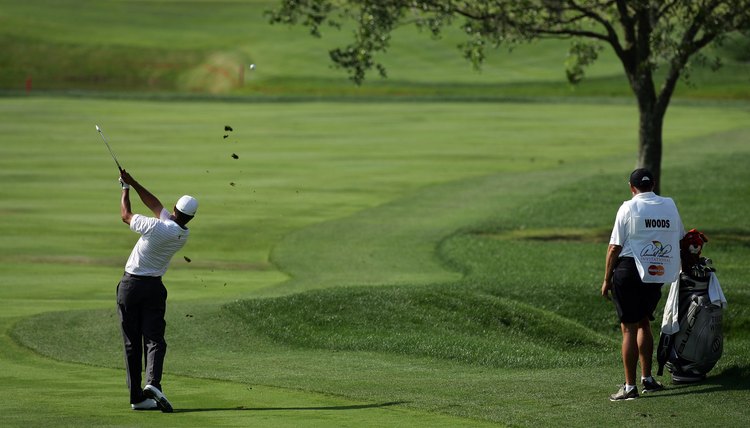 Tiger Woods fades the ball, shaping it around a tree.