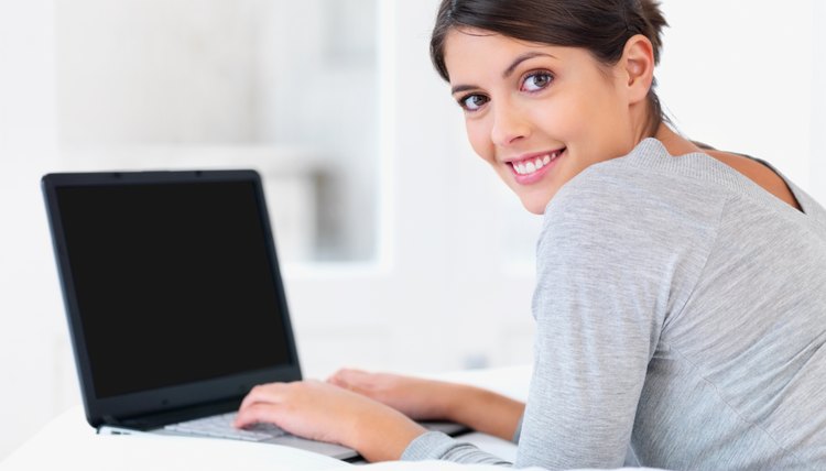 Young woman smiling in bed with a laptop
