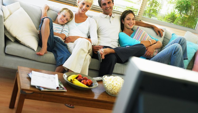 Family of four sitting on sofa, smiling, portrait