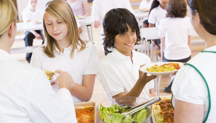 Lunchladies serving plates of lunch in school cafeteria