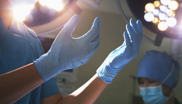 Midsection view of hands in surgical gloves and lights