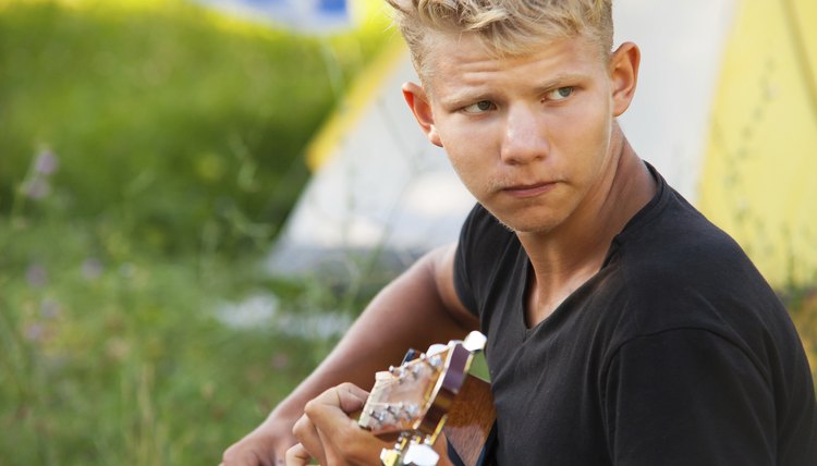Young man plaing by guitar