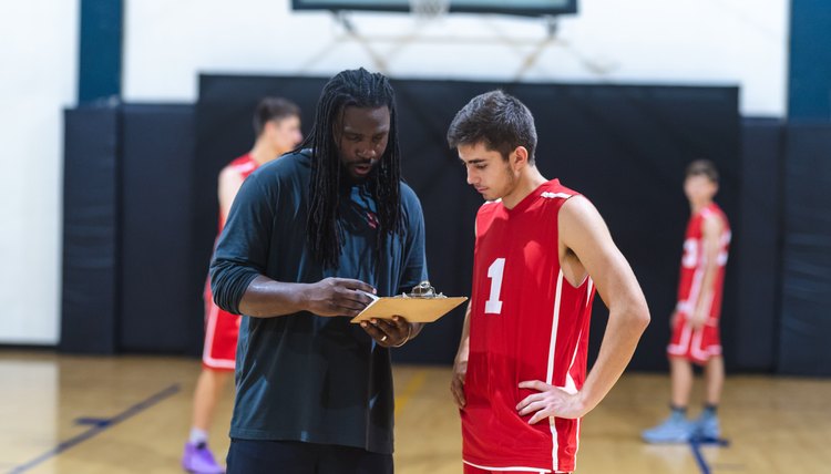 High school basketball coach goes over a play with one of his players