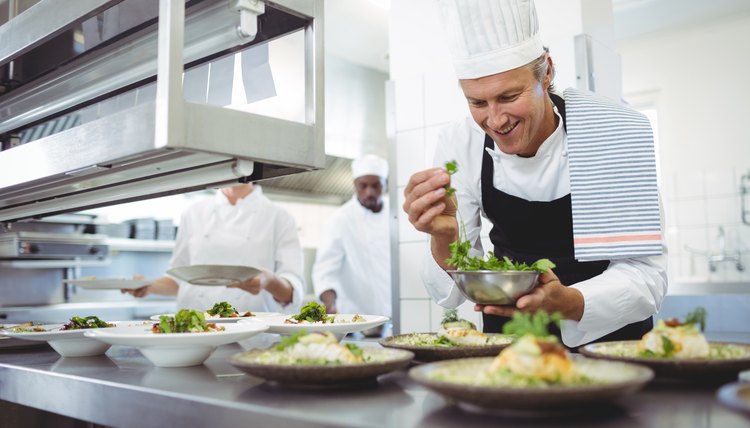 Happy chef garnishing appetizer plates at order station