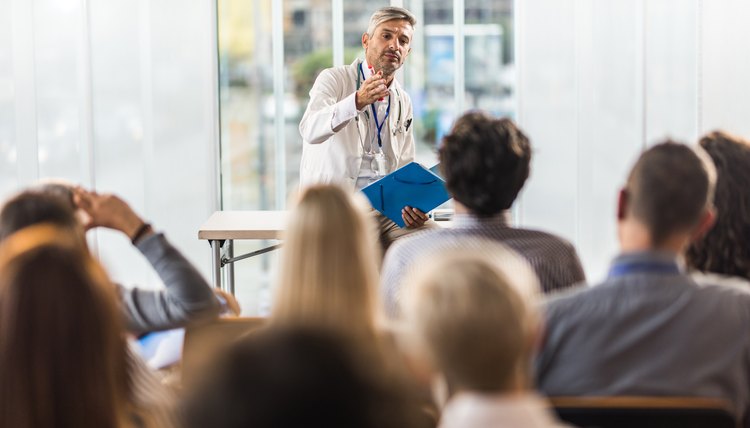 Mid adult doctor teaching on a seminar in a board room.