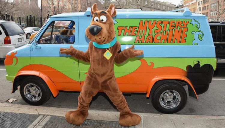 A man in a Scooby-Doo costume standing in front of a replica of the Mystery Machine van