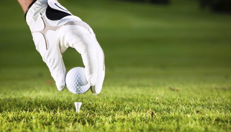 Close-up of a hand placing a golf ball on a tee