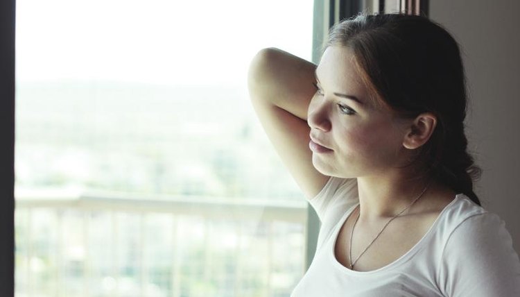 A contemplative woman thinking while looking out of a window.