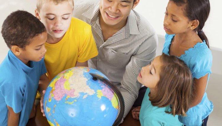 Young students and their teachers looking at globes.