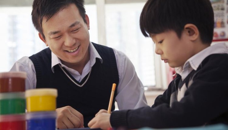 Teacher working with student at desk.