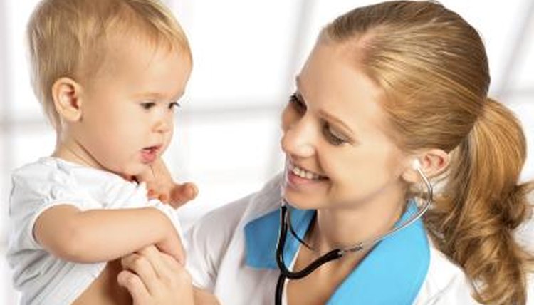 A young pediatric doctor is holding a young baby.