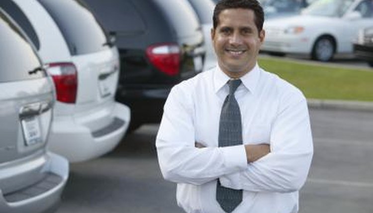 A car salesman stands in his dealership lot