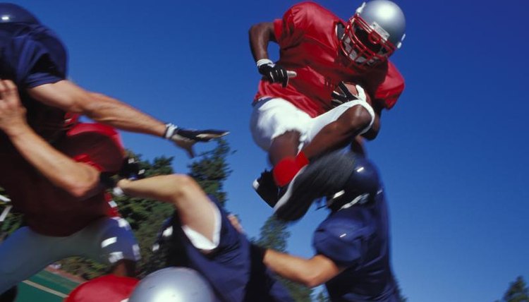 A football player jumps over a crouching player of the opposite team