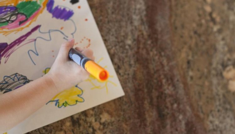 Little girl drawing on kitchen counter