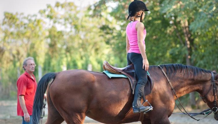 A man is teaching a young girl how to ride.
