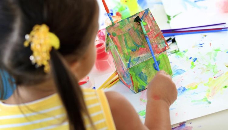 Child painting a small home model