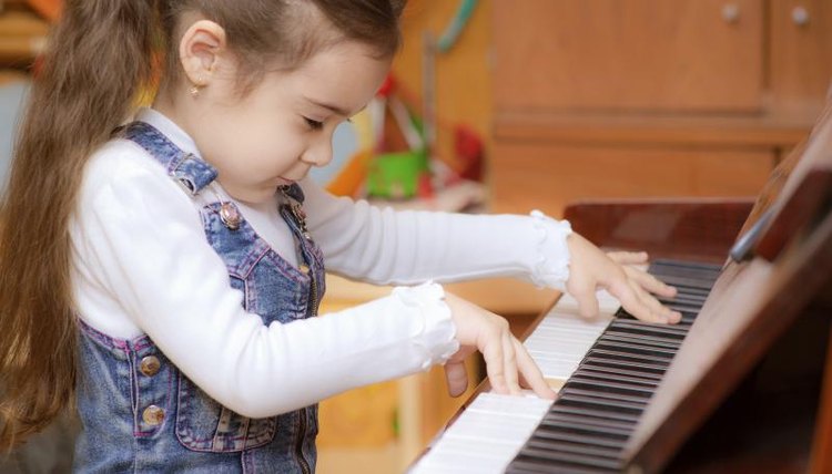 Preschooler playing on small piano.