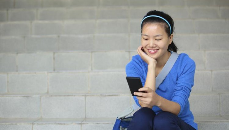 A student sits on stairs looking at her smart phone.
