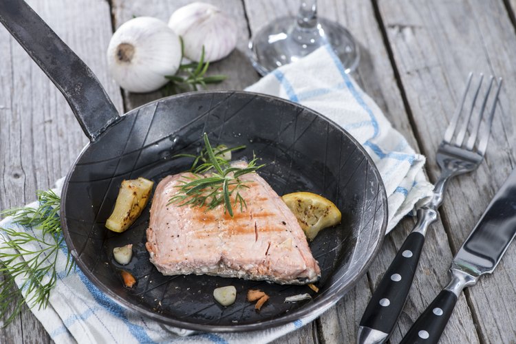 El salmón frito en una sartén con limón y hierbas