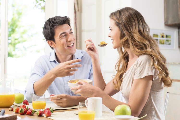 Una pareja feliz disfrutando del desayuno en la cocina.