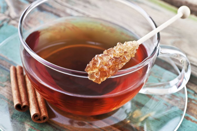 Varita de azúcar balanceándose sobre una taza de té.