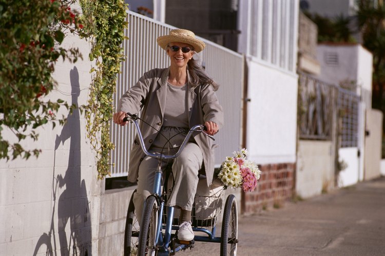 Una señora andando en una bicicleta de tres ruedas de estilo vertical con una cesta detrás.