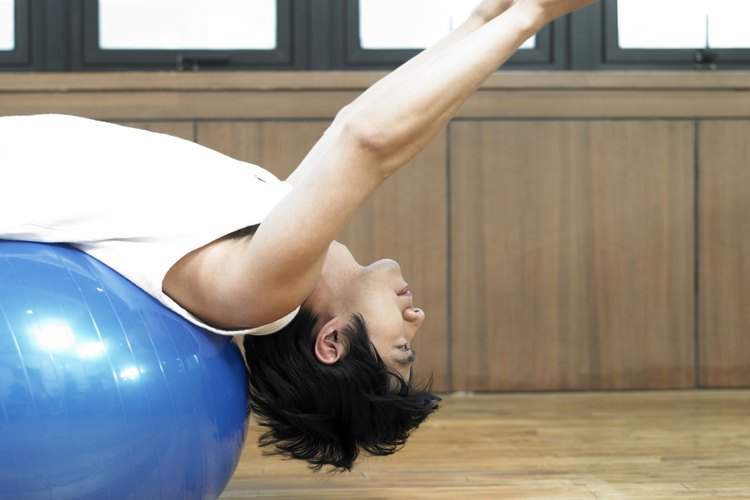 Hombre estirándose en una pelota de fitness.