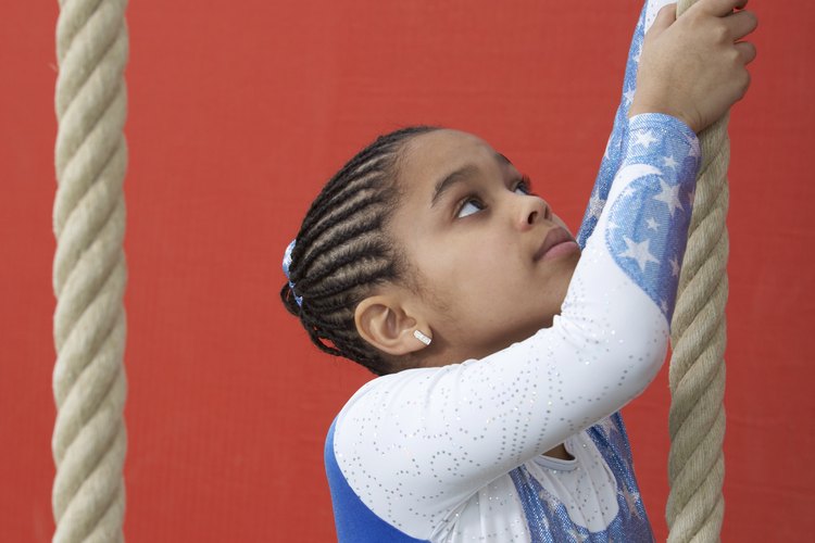 En vez de levantar pesas, las jovenes gimnastas suben cuerdas para desarrollar su fuerza.