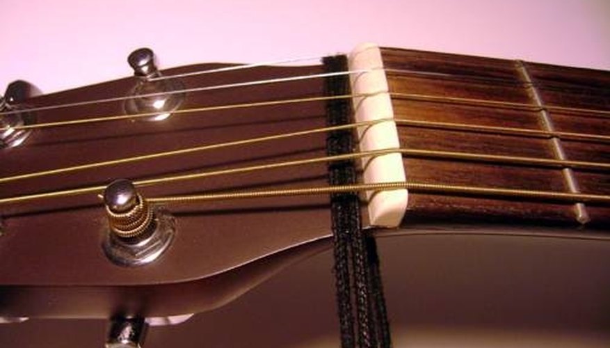 Tie the string just behind the nut and under the strings. Tie the string just behind the nut and under the strings.