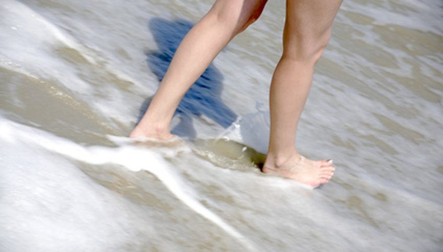 Photo Credit: Legs into the surf image by Pezography from <a href='http://www.fotolia.com'>Fotolia.com</a> Slave anklets can dress up your ankles when going barefoot.